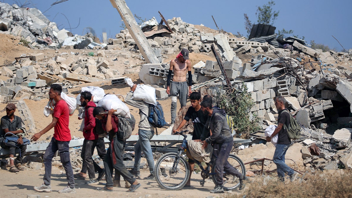 Palestinians carry sacks of aid past rubble