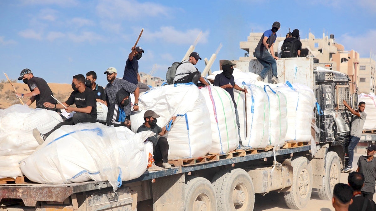 Hamas terrorists carrying clubs and firearms secure and divert humanitarian aid trucks in the northern Gaza area of Jabaliya on June. 25