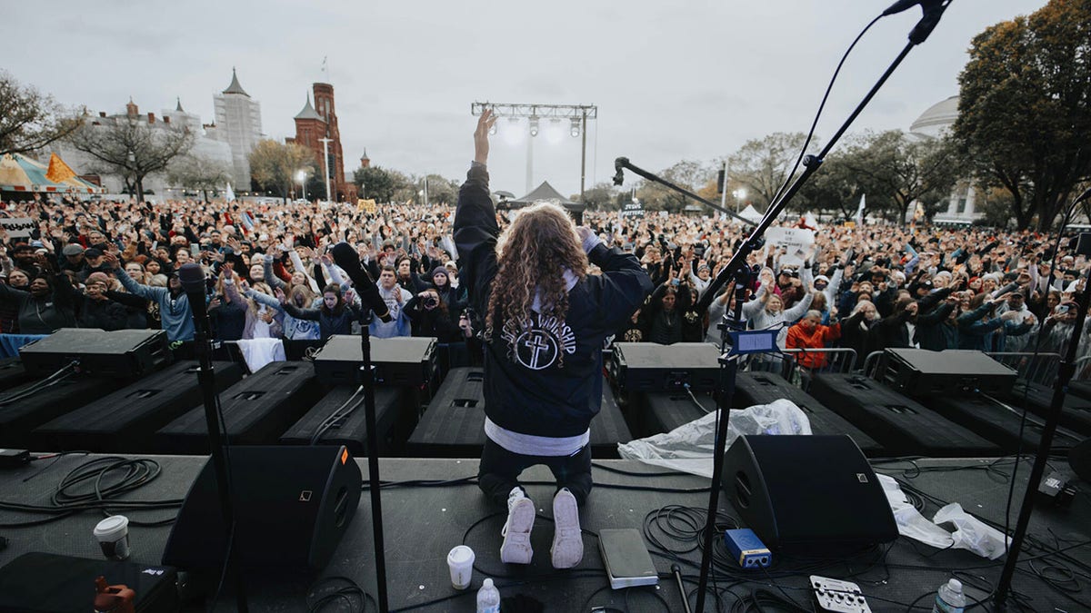 Worship leader Sean Feucht performing on stage kneeling