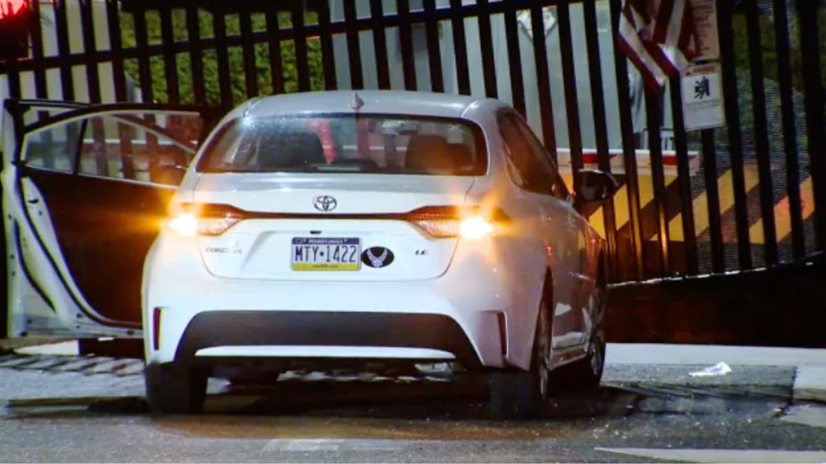 White sedan lodged against bent metal gate outside FBI Pittsburgh office at night