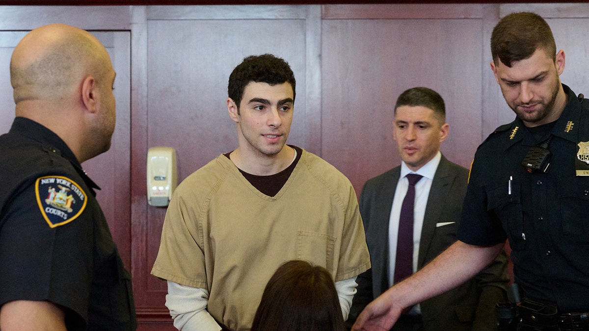 Luigi Mangione seated in court as judge drops terrorism charges.