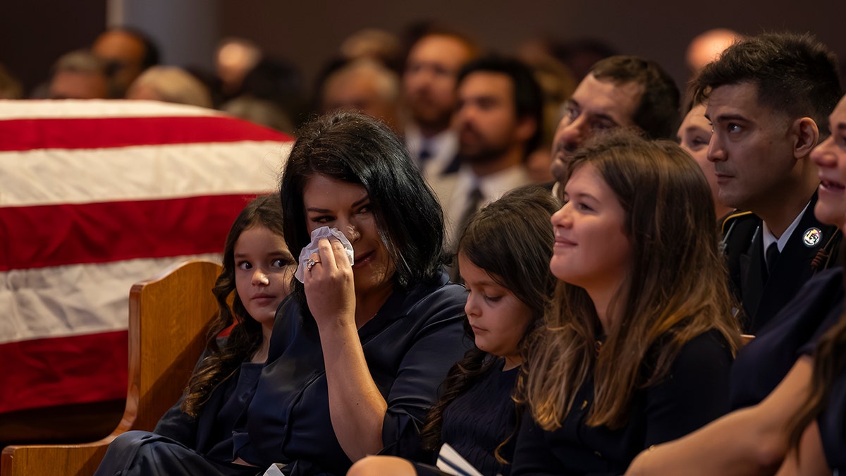 Sarah Verardo wipes away tears beside her daughters during Sgt. Michael Verardo’s funeral.