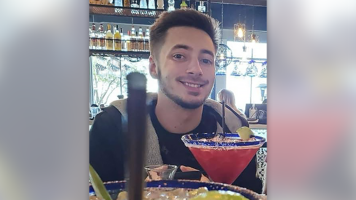 Kenneth Cutting Jr. wearing a jacket and T-shirt while sitting at a restaurant, with margarita glasses visible in the foreground