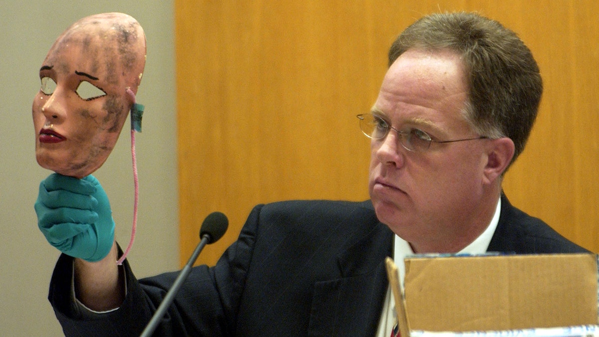 An investigator holding BTK's dirty woman mask.