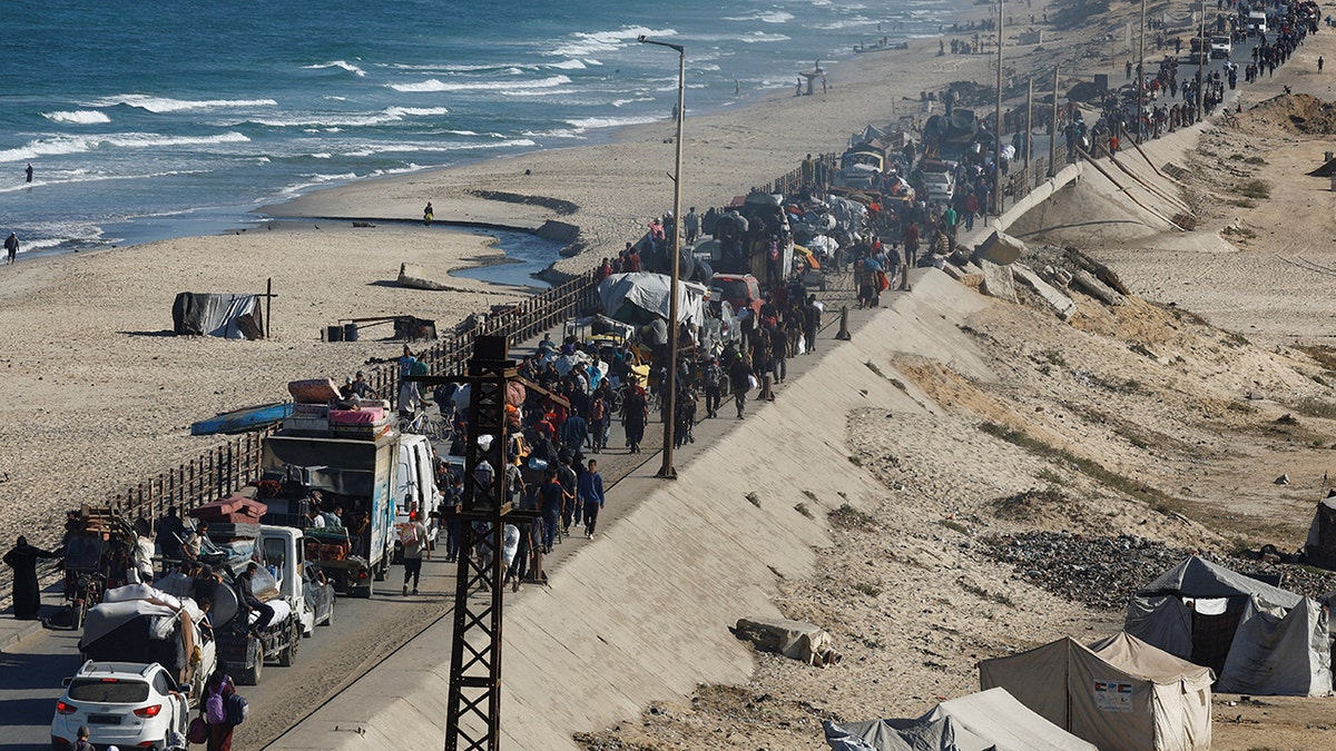 Displaced Palestinians walk north along road during ceasefire