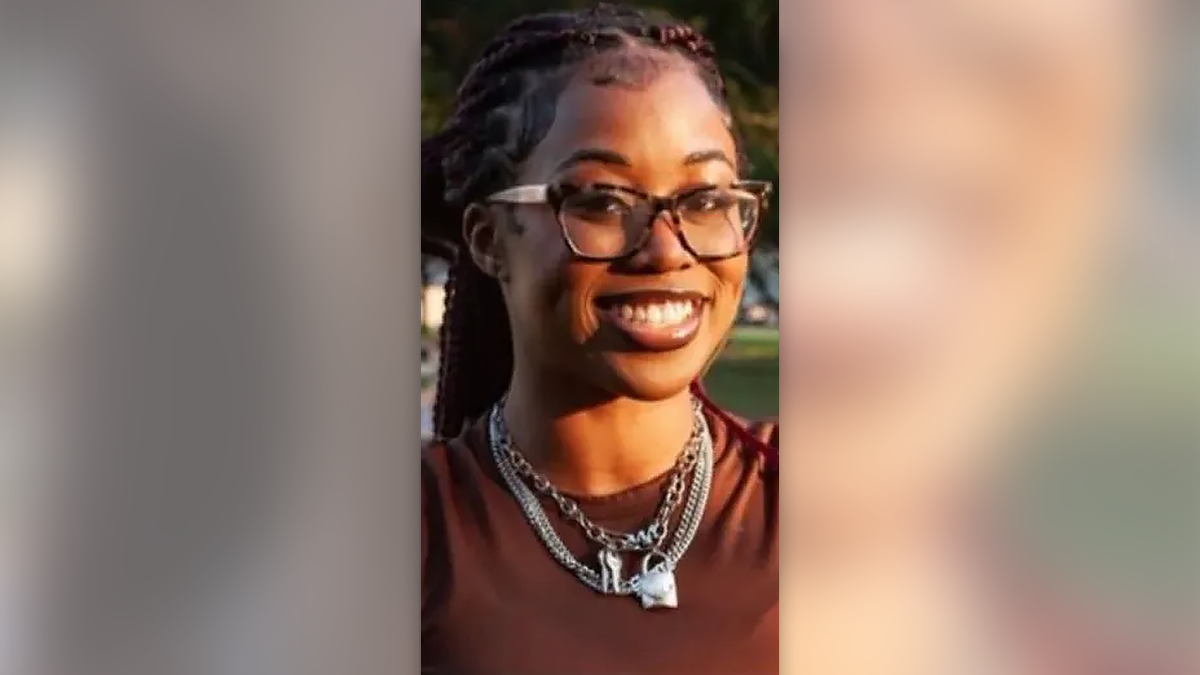 Jade McKissic wearing a burgundy shirt, silver necklaces and glasses