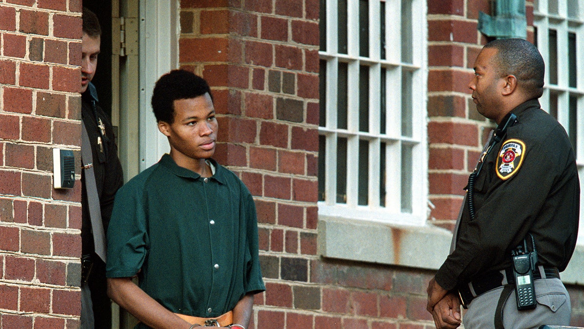 Lee Boyd Malvo in handcuffs being escorted by police.