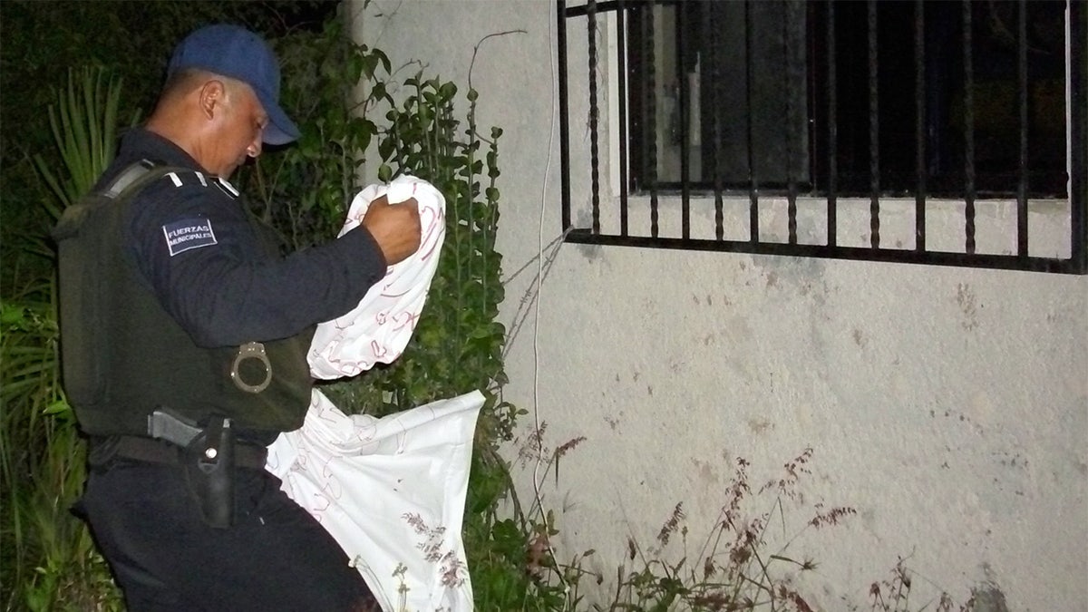 A police officer removes a banner allegedly hung by a drug gang in a house of Playa del Carmen