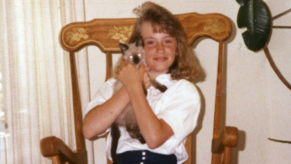 A young Rebecca Lafferty holding onto a kitten.