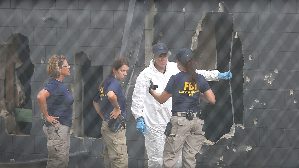 FBI agents stand near a concrete wall where a SWAT team had previously blown a hole to stop the Orlando nightclub shooter