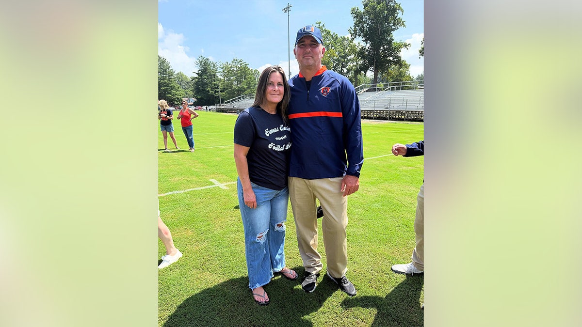 Leslie and Travis Turner smiling in a photo on a football field.