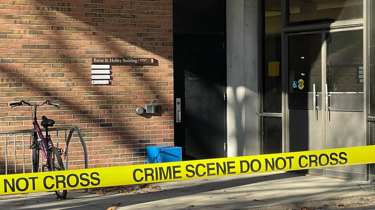 A bicycle and crime scene tape outside a door at the Barus and Holley Building at Brown University.