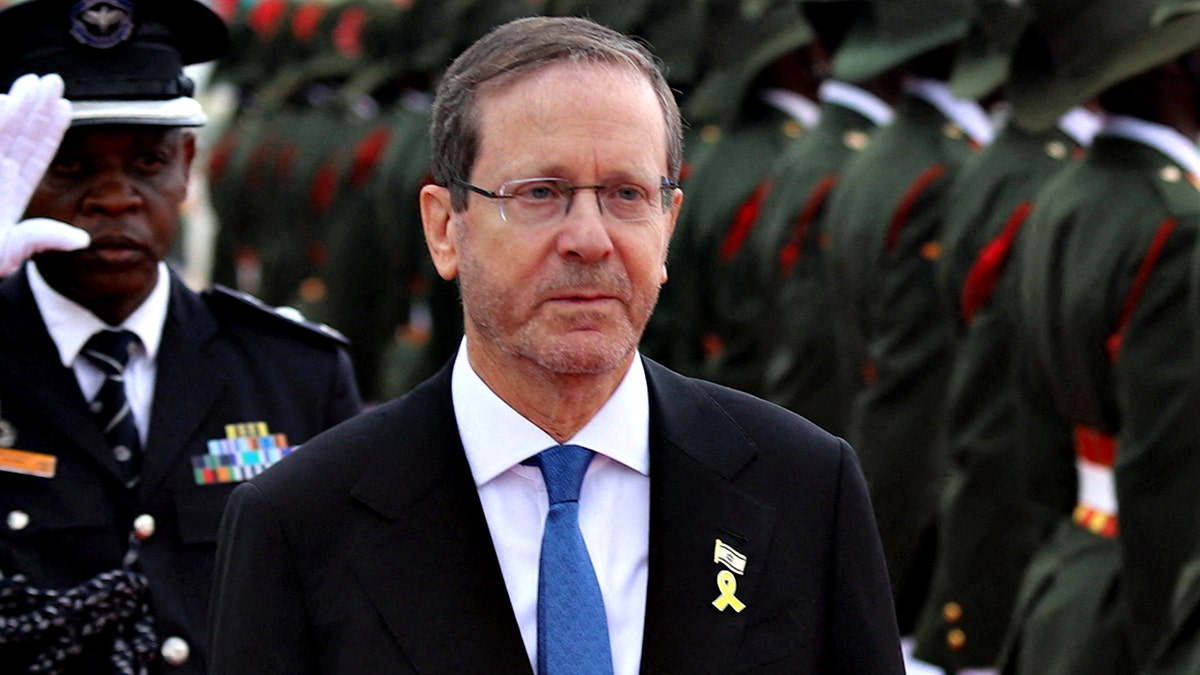 Israeli President Isaac Herzog looks stern as he walks