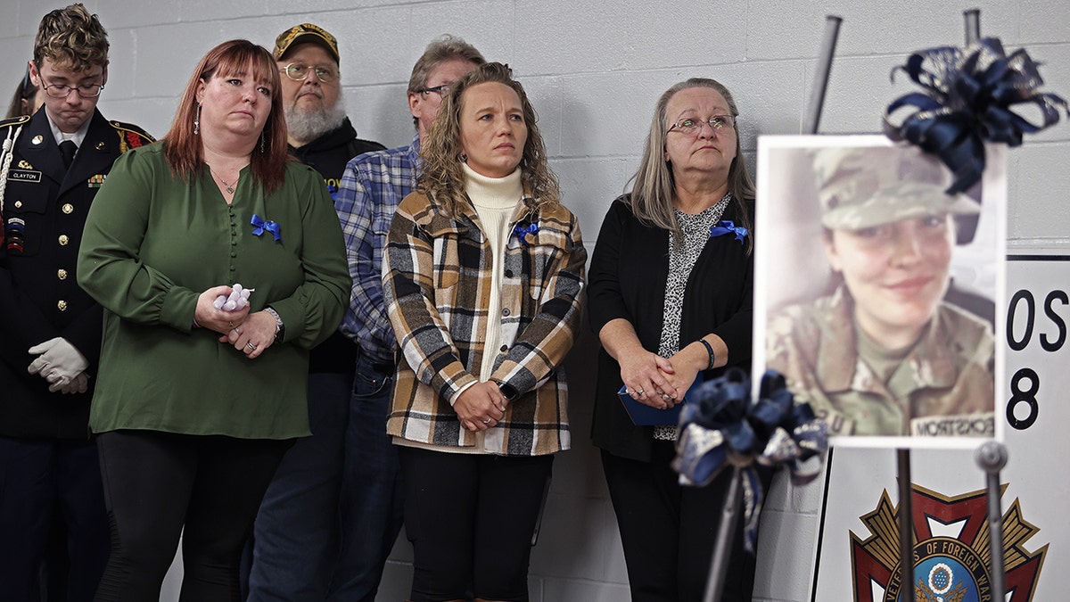 People in West Virginia stand next to poster of Sarah Beckstrom