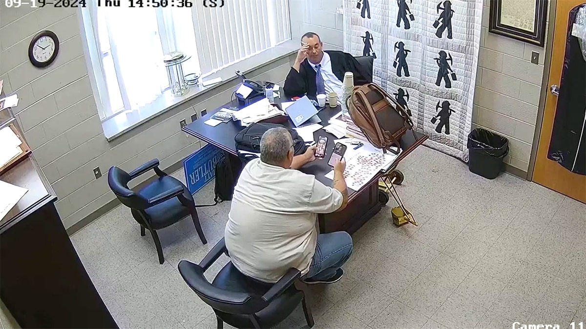 Sheriff Mickey Stines and Judge Kevin Mullins exchange cell phones in Mullins' chambers.