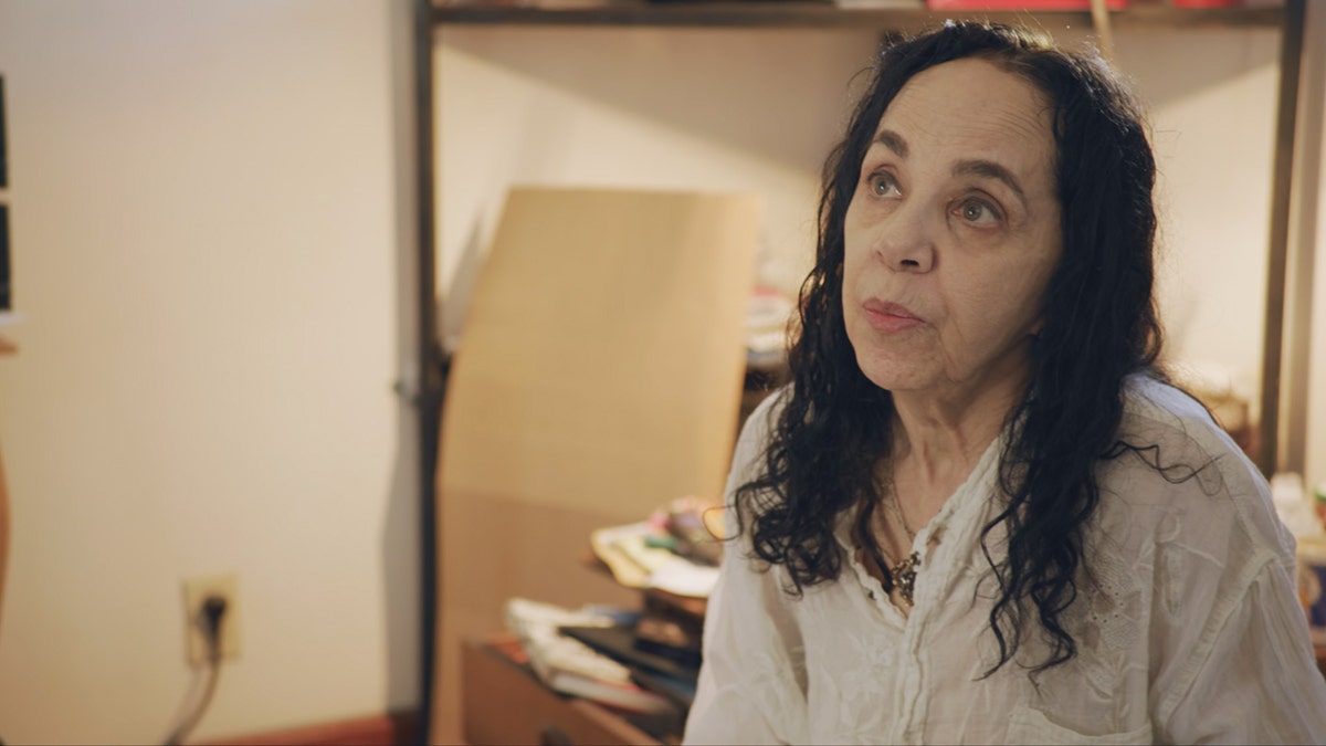 Laura Greenberg in a white blouse looking up.