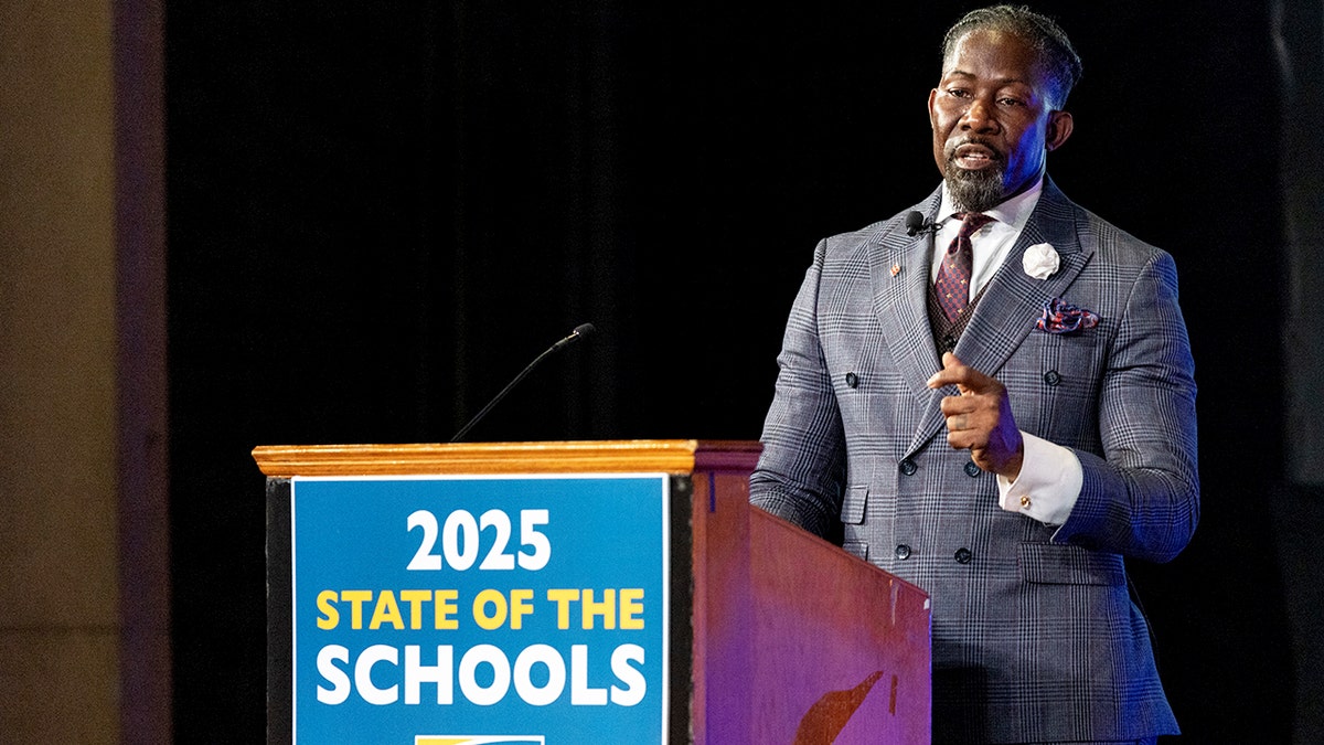 Ian Roberts speaks at podium at high school in Iowa