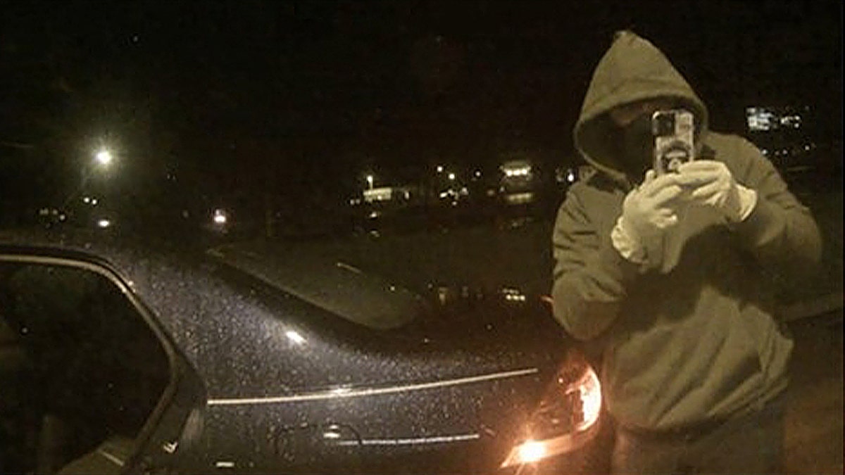 Hooded suspect records vehicle at night
