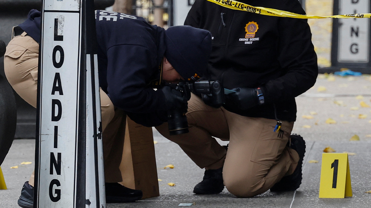NYPD crime scene investigators photograph a shell casing at the Brian Thompson murder scene in NYC
