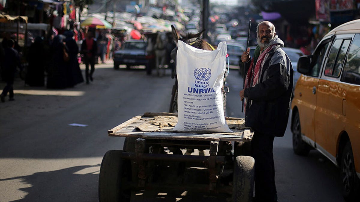A Palestinian man stands next to a cart carrying a flour sack distributed by the United Nations Relief and Works Agency (UNRWA) in Khan Younis refugee camp in the southern Gaza Strip January 3, 2018. REUTERS/Ibraheem Abu Mustafa - RC115BF78D00