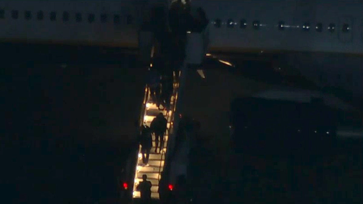 Persons escorted out of plane believed to carry Maduro, wife after Operation Absolute Resolve under cover of darkness.