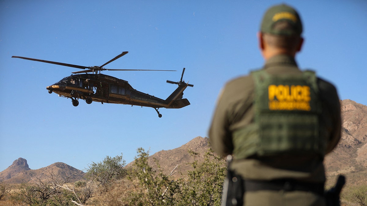 A border patrol agent watches a helicopter