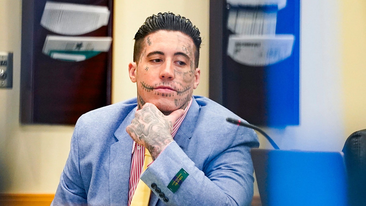 Wade Wilson in a light blue suit and a yellow tie with a pink shirt in court.